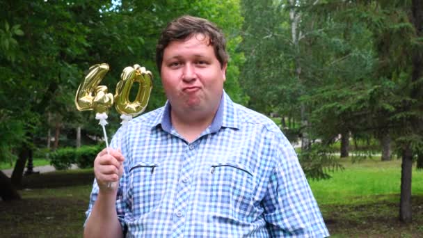 Big Man trzyma złote balony dokonywania 40 numer na zewnątrz. Jubileusz 40-lecia uroczystości — Wideo stockowe