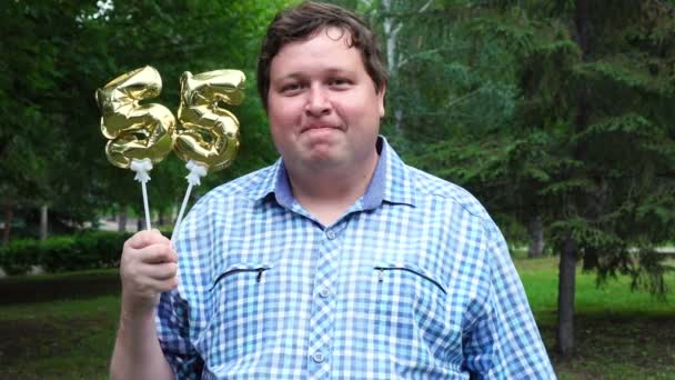 Μεγάλος άνθρωπος κρατώντας χρυσά μπαλόνια κάνοντας τον αριθμό 55 υπαίθριο. 55 η επέτειος πάρτι εορτασμού — Αρχείο Βίντεο
