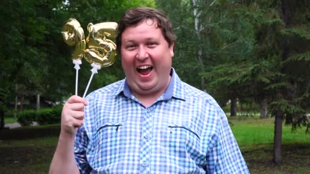 Big man holding golden balloons making the 95 number outdoor. 95th anniversary celebration party — Stock Video