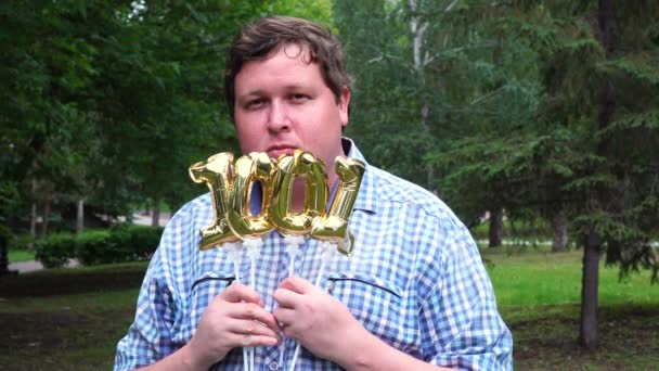 Big man innehar gyllene ballonger gör 1001 nummer utomhus. 100-års jubileum fest — Stockvideo