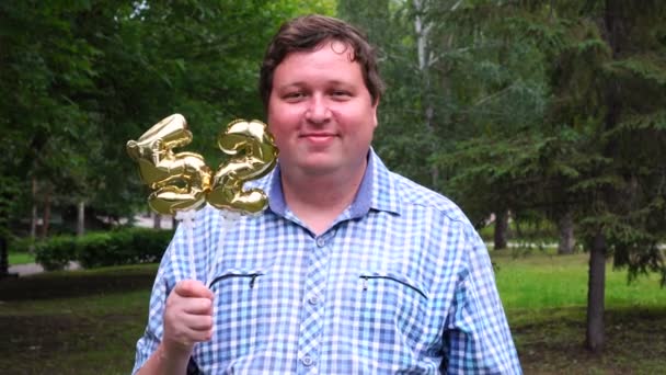 Grote man met gouden ballonnen maken van de 52 nummer buiten. 52ste verjaardag feest — Stockvideo