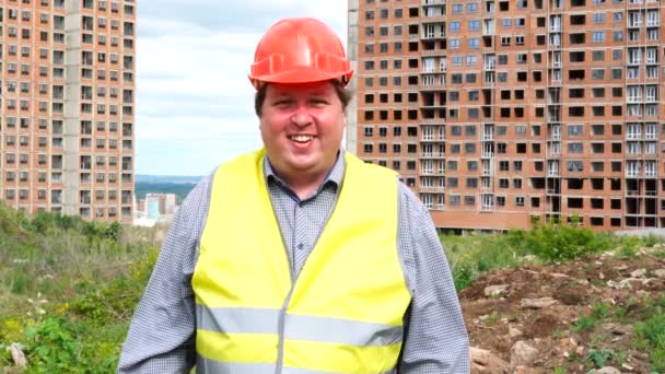 Hombre capataz constructor, trabajador o arquitecto en el sitio de construcción de pie mientras ríe y sonríe a la cámara — Vídeos de Stock