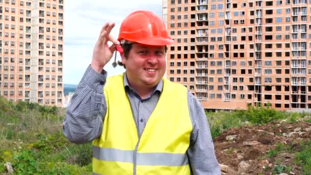 Mannelijke bouwer voorman, arbeider of architect op bouwplaats site tonen nieuwe thuis sleutel terwijl glimlachend naar camera — Stockvideo