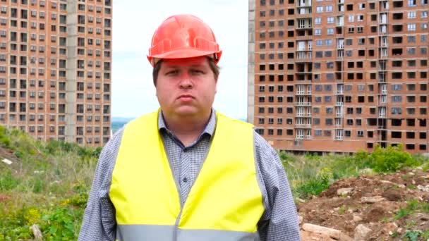 Mannelijke bouwer voorman, arbeider of architect op bouwterrein kijken naar camera emotieloze — Stockvideo