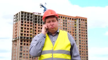 Erkek inşaat ustası, işçi veya mimar inşaat şantiye onun telefon ile konuşurken