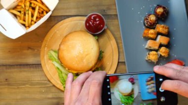 Trendy adam onu sosyal topluluk üzerinde paylaşım için taze lezzetli büyük burger öğle yemeği fotoğrafı alarak akıllı telefon kullanarak.