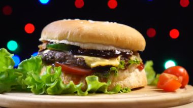 Serin güzel taze sulu pişmiş burger renkli bulanık ışıklar bir arka plan karşı pikap üzerinde döndürmek.