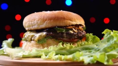 Serin güzel taze sulu pişmiş burger renkli bulanık ışıklar bir arka plan karşı pikap üzerinde döndürmek.