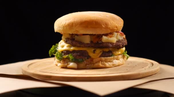 Hambúrguer apetitoso fresco girando sobre fundo preto . — Vídeo de Stock