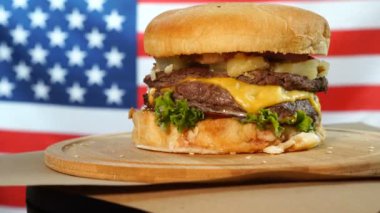 Marul, peynir, soğan ile ızgara Amerikan sığır burger ahşap bir tezgah üzerinde dönen kahverengi kağıt parçaları üzerinde servis.