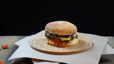 Taze iştah açıcı hamburger siyah arka plan üzerinde dönen. Sorunsuz döngülenebilir çekim