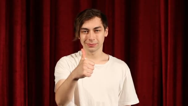 年轻人竖起大拇指在红色窗帘背景 — 图库视频影像