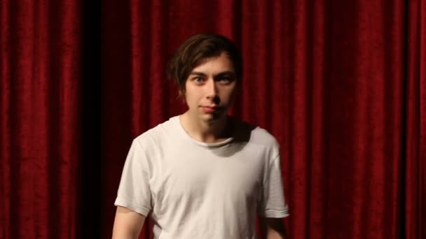 Young man dancing against red curtain background — Stock Video