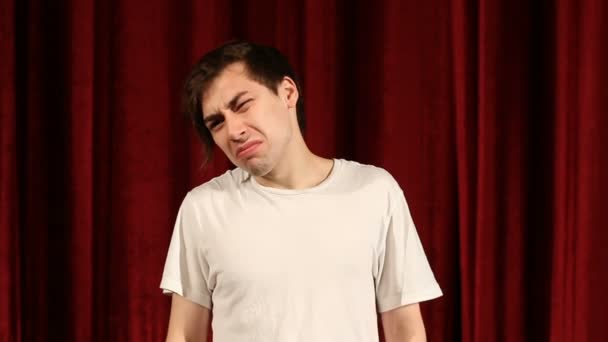 Młody nieszczęśliwy człowiek przed czerwonym tle kurtyny — Wideo stockowe