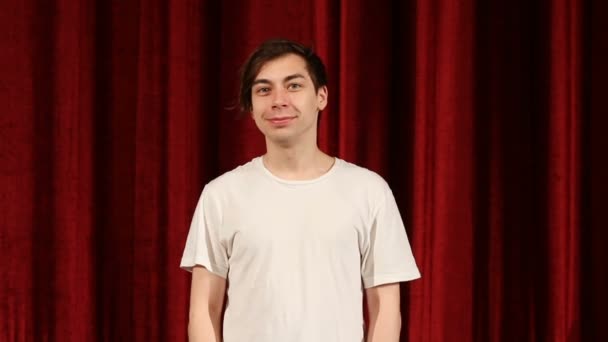 Junger glücklicher Mann lächelt vor rotem Vorhang — Stockvideo