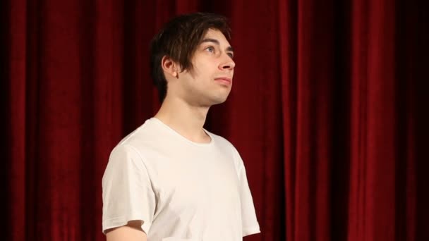 Профиль бокового вида молодого человека, стоящего у красных штор — стоковое видео