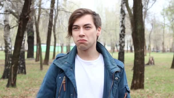 Retrato de guapo caucásico joven feliz mostrando signo de paz en el parque — Vídeos de Stock