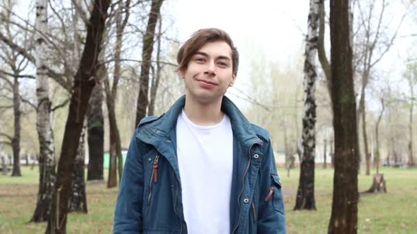 Portrét hezkého kavkazského šťastného mladého muže, který se usmívá na kameru v parku — Stock video