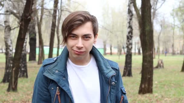Portréja csinos kaukázusi boldog fiatalember bemutató fasz a parkban — Stock videók