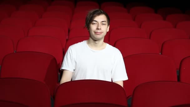 Man sitting alone in empty cinema hall or theater — Stock Video