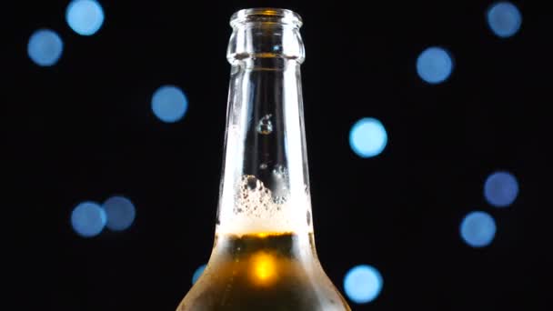 Bier fles close-up. Licht bier in fles gedraaid over zwarte achtergrond. — Stockvideo