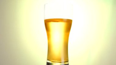 Hafif Bira yakın çekim. Beyaz arka plan üzerinde döndürülen mat sarı arka plan üzerinde izole soğuk ışık bira pint.