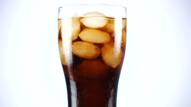 Glass of cola turns slowly around its axis. Close up 4K video. White background. — Stock Video