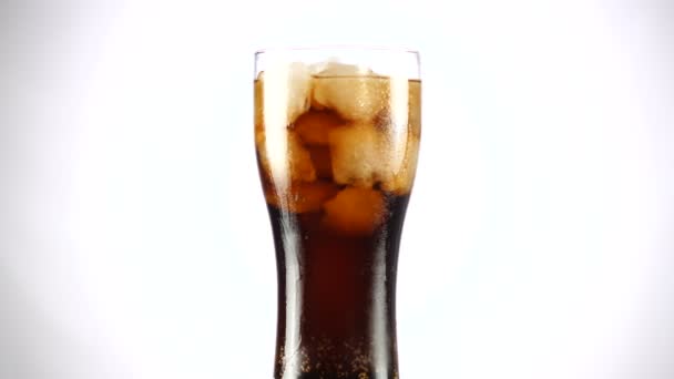 Glas av Cola med iskuber vänder långsamt runt om dess axel. Stäng 4K-video. Vit bakgrund. — Stockvideo