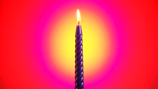 Blaue Kerze brennt und dreht sich auf dem leuchtend roten Hintergrund — Stockvideo