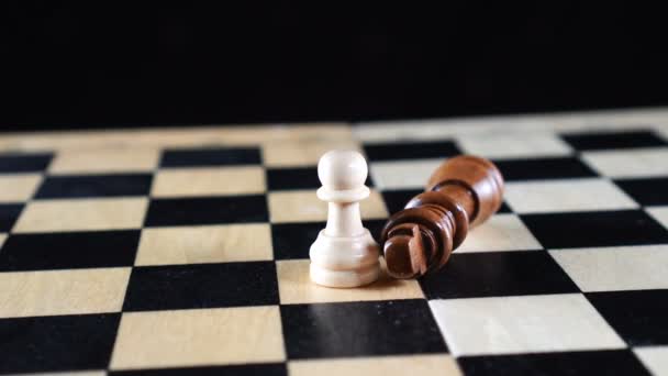 Dos peones de ajedrez y el rey con la pieza de ajedrez negro vencido acostado en su lado y el peón blanco de pie — Vídeos de Stock