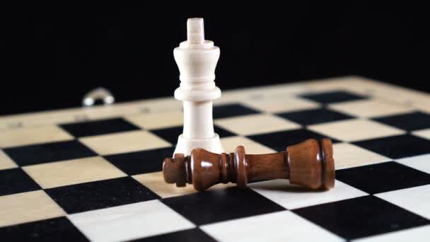 Two chess kings with the vanquished black chess piece lying on its side and the white king standing upright — Stock Video