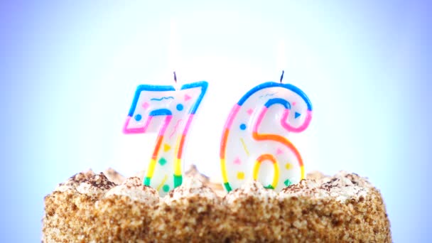 Bolo de aniversário com uma vela de aniversário ardente. Número 76. Fundo muda de cor — Vídeo de Stock
