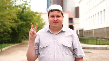 Şehirde genç Müslüman adam gösteren, zafer veya barış işareti yapma