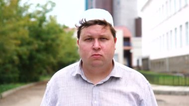 Şehirde genç Müslüman adam kameraya bakıyor