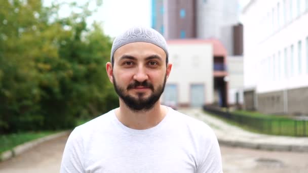 Vousatý muslimský muž ve městě a dívá se na kameru — Stock video