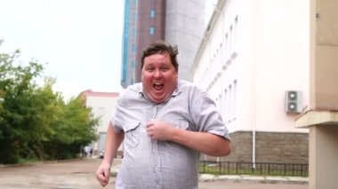 Mutlu şişman adam şehir caddesi boyunca koşar. Adam başarı için ısınır ya da kilo vermeye başlar