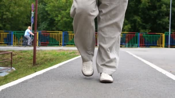 Hombre piernas en zapatos blancos caminando en baldosas camino al aire libre — Vídeo de stock