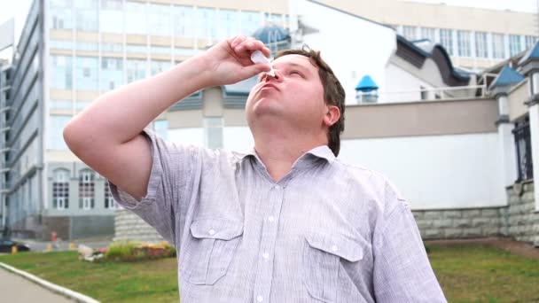 Sjukdomar och sjukdom. Stilig man mår illa droppande näsdroppar i blockerad näsa utomhus. — Stockvideo
