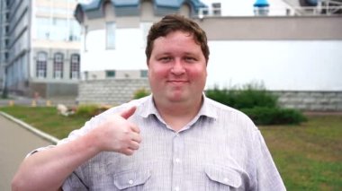 Yakışıklı gülümseyen genç adam portre kim başparmak gösteren. Kameraya bakan duygusal erkekler