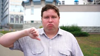 Yakışıklı gülümseyen genç adam portre başparmak aşağı gösteren. Kameraya bakan duygusal erkekler