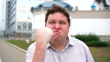 Bir yumruk gösteren ve kontrolünü kaybetmek Yakışıklı öfkeli genç adam portre. Kameraya bakan duygusal erkekler