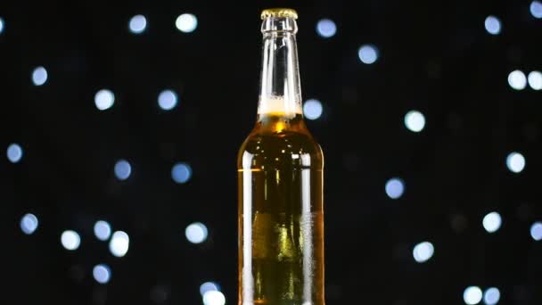 Бледное пиво в прозрачной бутылке, вращающейся на черном фоне с яркими огнями — стоковое видео