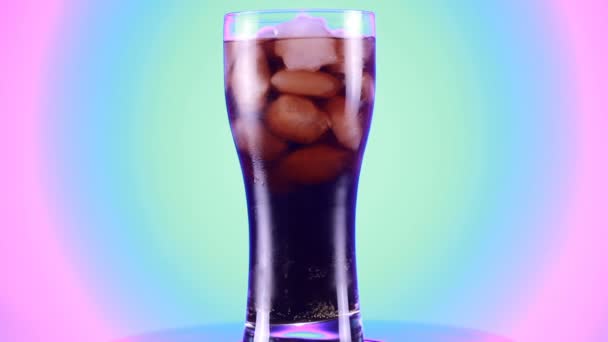 Gedrehtes Glas Cola-Spritzgetränk isoliert auf blauem Hintergrund. — Stockvideo