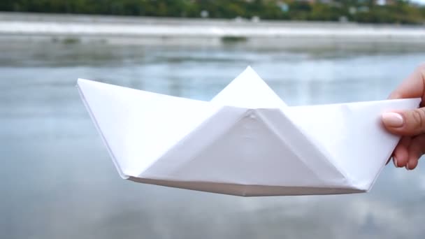 Womans hand holding white paper boat over the river — Stock Video