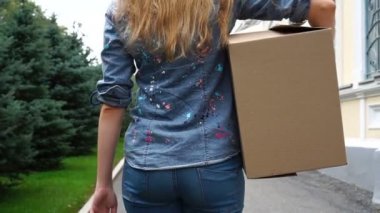 Karton kutu taşıyan ve dışarıda yürüyen kadının arka görünümü