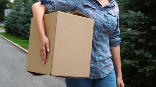 Mujer irreconocible llevando una caja de cartón y caminando al aire libre — Vídeo de stock