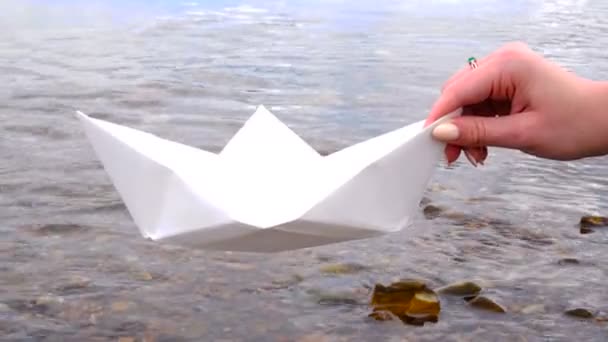 Womans hand holding paper boat over the river — Stock Video