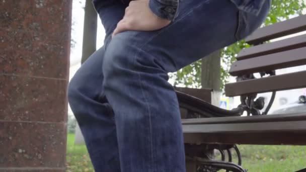 Άνθρωπος στέκεται όρθιος από τον πάγκο νιώθοντας έντονο πόνο στο γόνατο στο πάρκο, την οστεοαρθρίτιδα, τραυματισμό — Αρχείο Βίντεο