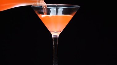 Martini bardağına portakal kokteyli dökülüyor.