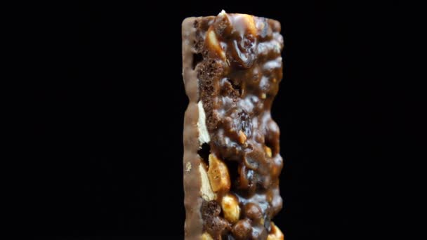 Muesli bedekt met chocolade, gezond eten chocoladereep draait op een zwarte achtergrond. — Stockvideo